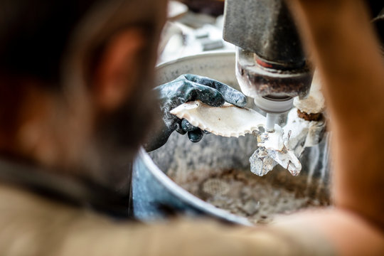 Midsection of worker making buttons with seashell in workshop