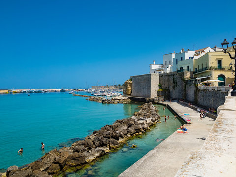 Italy, Province of Lecce, Otranto, People relaxing along shore of coastal town in summer