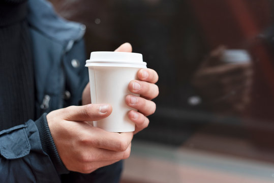 Young man holding a takeaway coffee outdoors