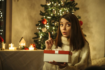 pensive woman thinking about idea of christmas gift with x-mas tree on background