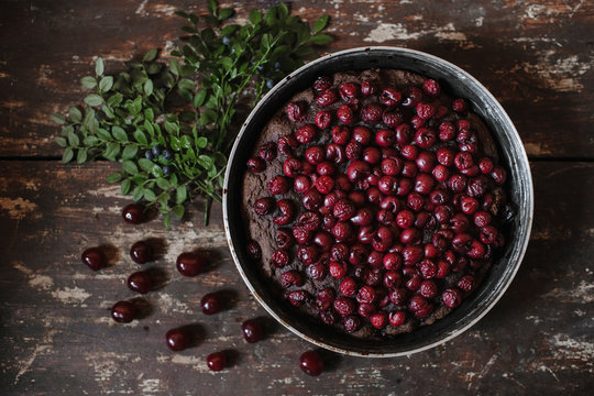 Directly above shot of brownie pie garnished with cherries by herbs on wooden table