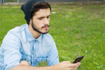 Young man using his phone. Outdoors.