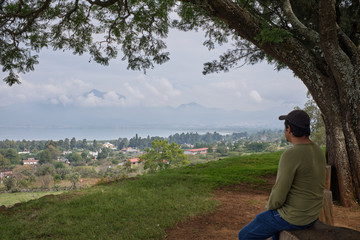 Hombre sentado viendo paisaje de lago de Patzcuaro desde zona arqueologica de Tzintzuntzan