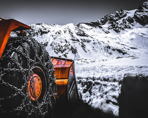 Snow plow truck with chains on wheels in the Graian Alps, Gran Paradiso, Italy at the top of the mountains. Located between the Aosta Valley and Piedmont regions. 