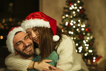 Fototapeta na wymiar woman hug man and laughting with santa claus hat; christmas celebraiting concept