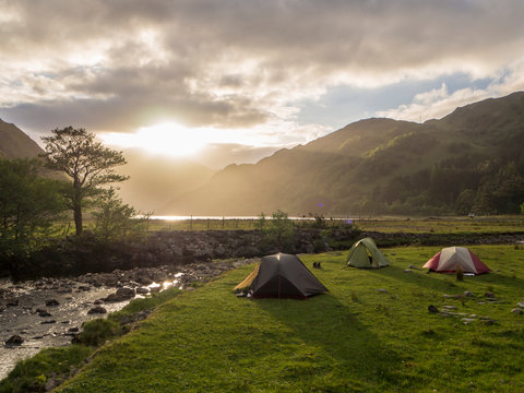 Tents on grassy land against cloudy sky during sunset, Scotland, UK