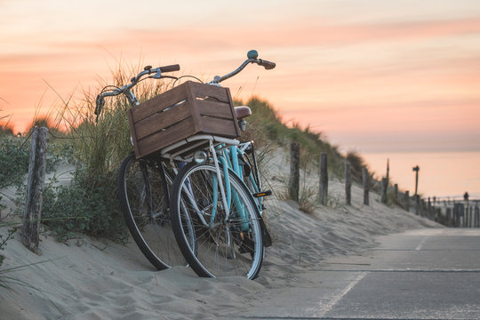 Netherlands, South Holland, Noordwijk, bicycles on sandy beach at sunset
