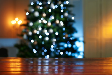 Close-up of wooden table with illuminated Christmas tree in background at home