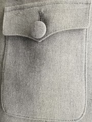 Close-up photo of light gray pocket with button. Abstract background on the subject of vintage clothes and fashion or money and finance.