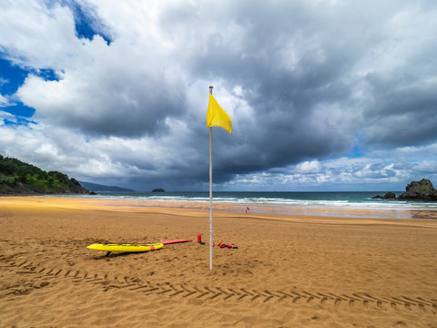 Yellow flag at Laga beach against cloudy sky, Spanish Basque Country, Spain