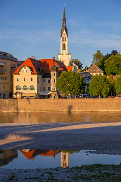 Parish Church of the Assumption and buildings by River Isar against sky in town, Bavaria, Germany