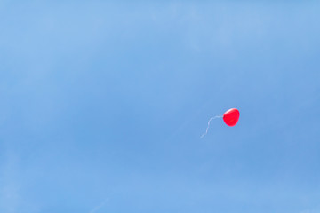 Low angle view of red heart shaped balloon flying against clear blue sky at wedding ceremony