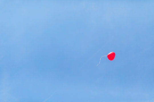 Low angle view of red heart shaped balloon flying against clear blue sky at wedding ceremony