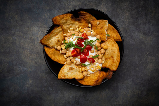 Bowl of Levantine fatteh, with flat bread, tomatoes and chickpeas