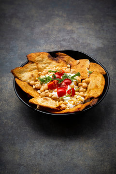 Bowl of Levantine fatteh, with flat bread, tomatoes and chickpeas