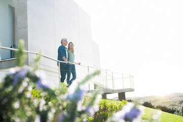 Smiling couple standing in front of their modern home