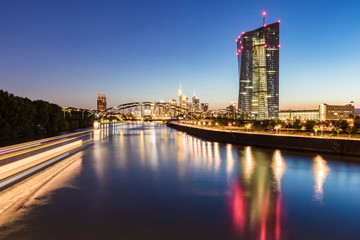 River in illuminated city against blue sky at night in Frankfurt, Germany