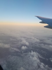 wing of airplane flying above the clouds