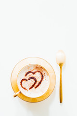 Cup of coffee on white background, copy space. Minimal flat lay with capuccino coffee  with a cocoa powder chocolate heart for Valentine day text, love and romance concept, top view.