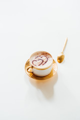 Cup of coffee on white background, copy space. Minimal flat lay with capuccino coffee  with a cocoa powder chocolate heart for Valentine day text, love and romance concept, top view.