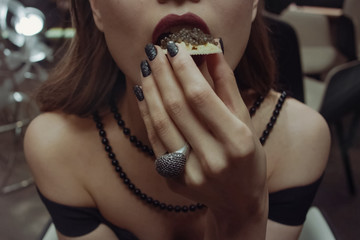 Woman eating sandwich with black caviar.