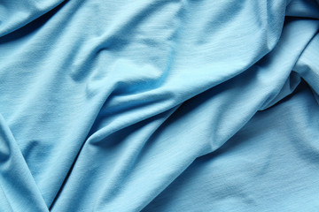 Fototapeta premium Light blue fabric texture with soft folds and natural wrinkles, textile background for fashion and design concepts