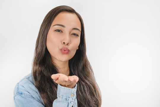 Close up portrait of cute female blows kiss at camera isolated over white background
