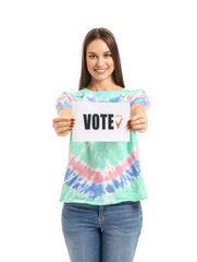 Young woman holding paper with text VOTE on white background