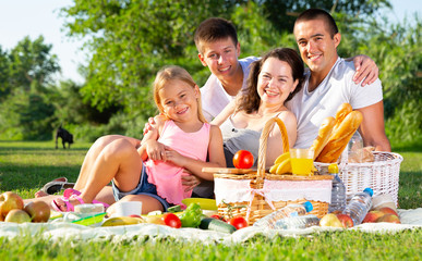 Parents with two teenagers enjoying  delicious meal on the picnic