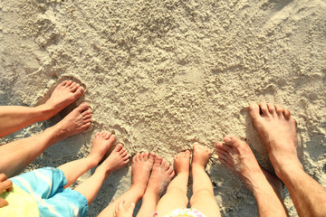 Family feet on the sand on the beach