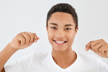 Portrait of teenage boy with dental floss on light background