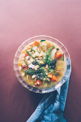 Minestrone recipe, tasting and writing rcipe on cook book about italian minestrone soup, on a glasses. with cherry tomato brown, lime, and link round pieces, with a blank diary to write and add text,