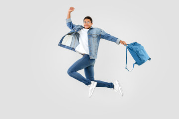 Jumping African-American teenager boy with backpack on white background