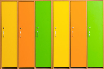 Background of the colored school cabinets. A long multicolored wall of small lockers with multicolored doors