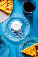 Quiche with.egg, cream, ricotta  cheese and cheeves leaves,, round shaped top view on a blue background