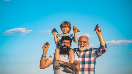 Young boy with father and grandfather enjoying together in park on blue sky background. Fathers day - grandfather, father and son are hugging and having fun together.