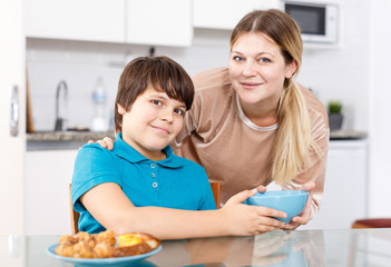 Mother and son eating at kitchen
