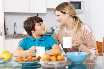 Mother and son eating at kitchen