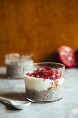 Chia parfait yogurt dessert with cereals and pomegranate seeds on a rustic environment