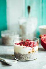 Chia parfait yogurt dessert with cereals and pomegranate seeds on a rustic environment