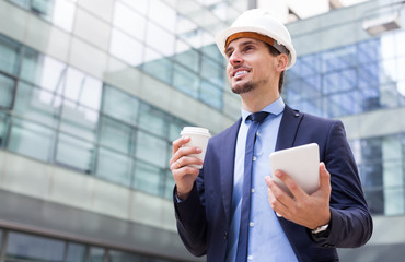 Smililng male in jacket and helmet working at tablet