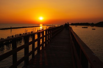 Plakat wooden pier at the sea with beautiful bloody sunset. sunset seascape at a wooden jetty. Wood bridge