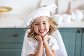 smiling cute girl in a chefs toque in kitchen