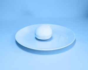 One pastel soft marshmallow on a turquoise plate. Total classic blue background.