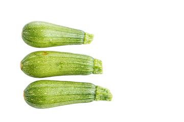 Calabacitas verdes enteras y en rebanadas sobre fondo blanco