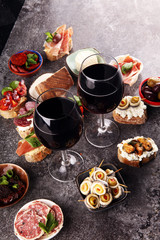 Appetizers table with italian antipasti snacks and wine in glasses. Brushetta or authentic traditional spanish tapas set, cheese variety