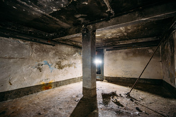 Dark and creepy dirty abandoned underground basement afrer fire. Walls in black soot