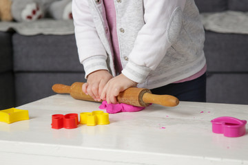 Toddler girl playing with modelling clay. Play dough allows kids to develop fine motor skills, strengthen fingers, hands and wrists and to be naturally curious and explore the world using their senses