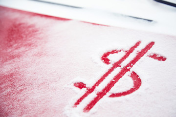 Dollar sign in the snow. Red dollar sign on a snowy car hood. The concept of an accident in bad weather, a large repair cost