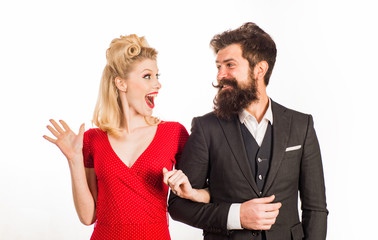 Funny retro couple. Blonde surprised woman in red dress looking at her bearded handsome future husband. Family photo of emotional young couple isolated at white background.